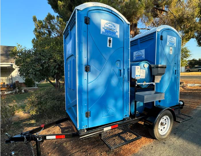 Double towable restroom trailer in Lemoore featuring two independent portable toilet units with integrated handwash stations and soap dispensers for large events.