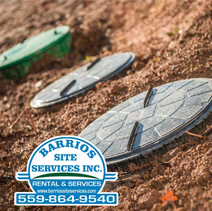 Close-up of durable septic tank lids installed in a commercial property's landscape, ready for professional septic system service and inspection.