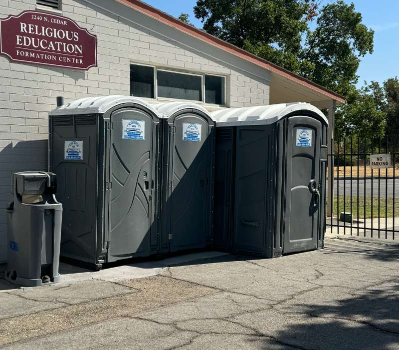Row of clean Barrios Site Services portable toilets and a standalone handwash station provided for a community event at a religious education center, ensuring reliable sanitation for large public gatherings.